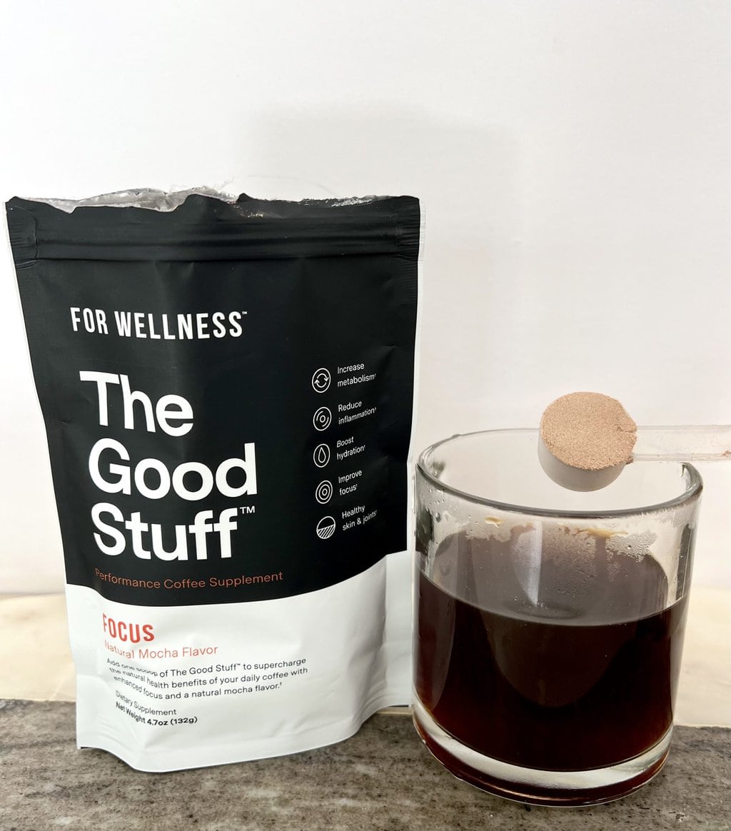 A pack of For Wellness The Good Stuff Focus stands next to a brewed cup of coffee