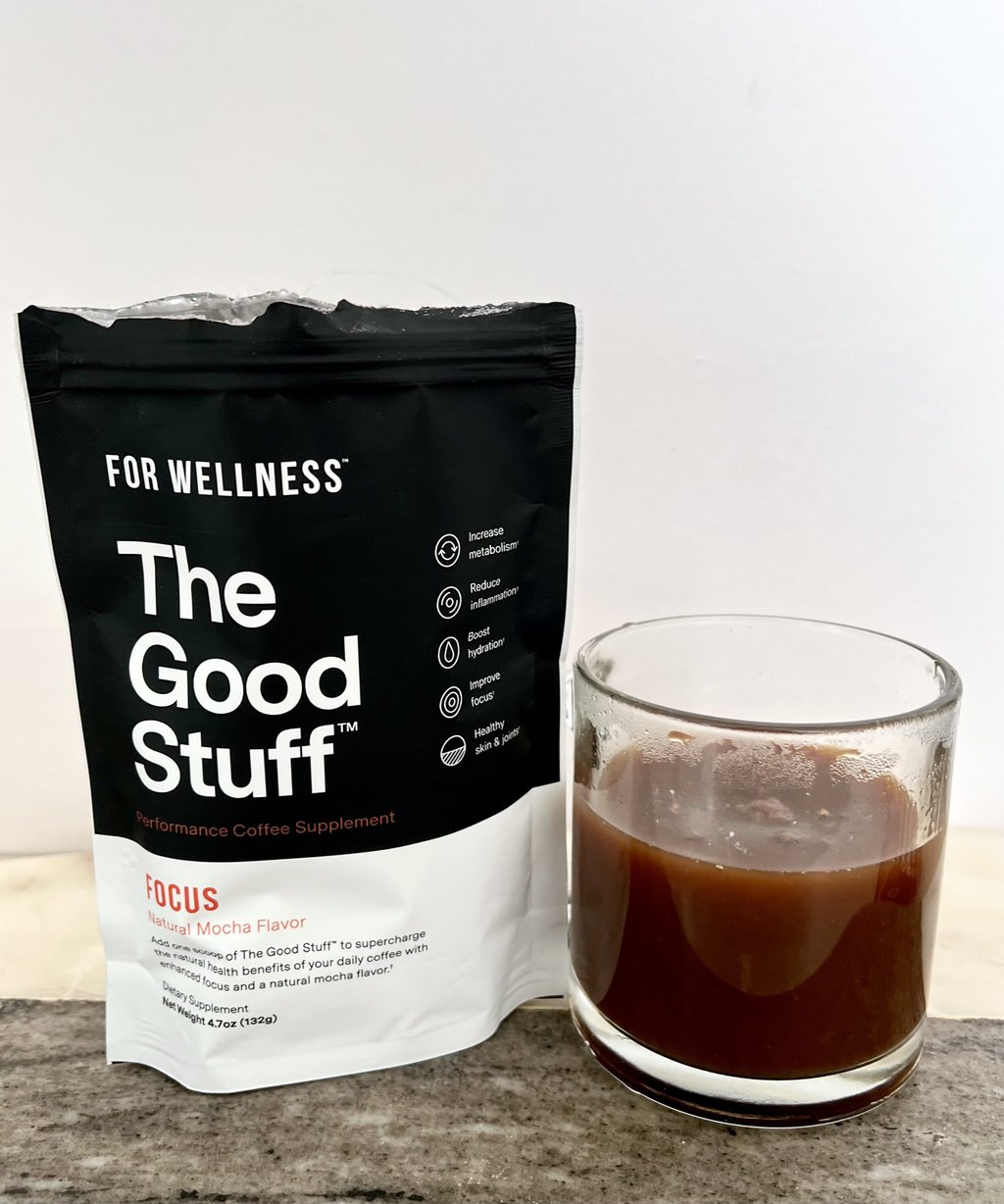 an open package of For Wellness The Good Stuff Focus stands next to a cup of liquid