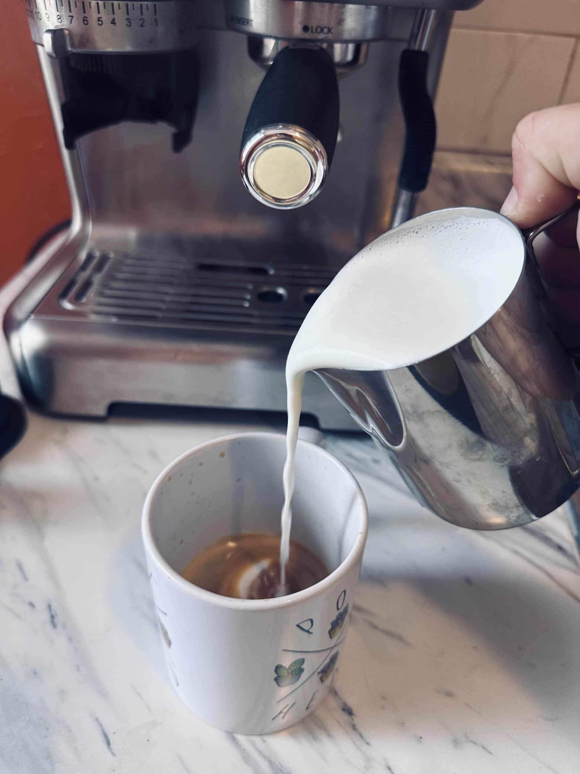 brewed milk is poured into a cup of espresso