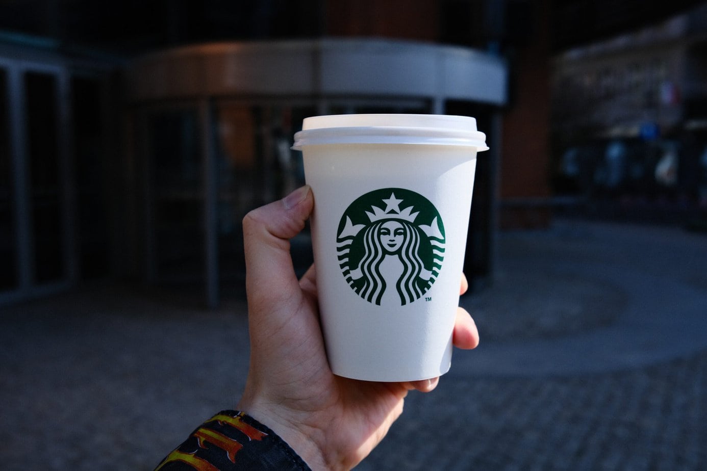 Person Holding white Cup with logo Starbucks