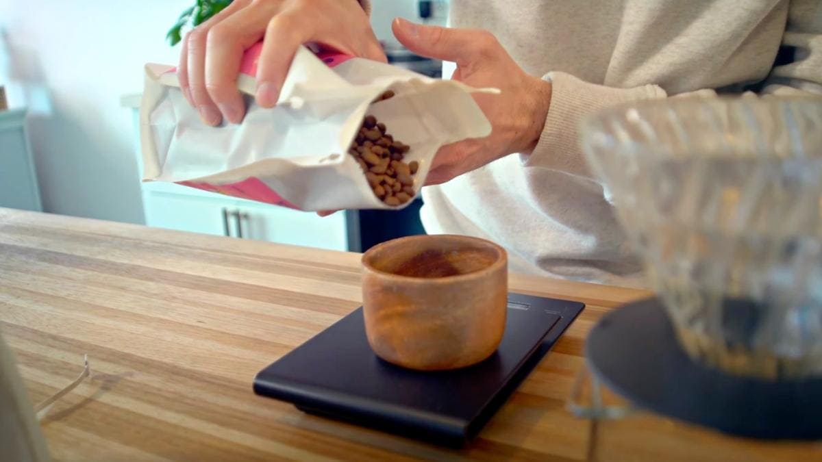 man pouring Creature Coffee beans into a bowl