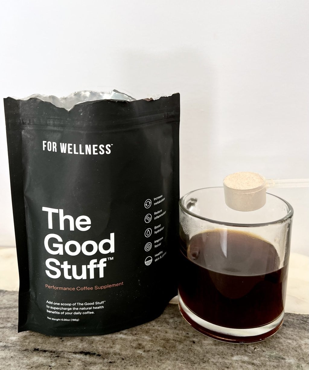 For Wellness The Good Stuff package is next to a brewed cup of coffee